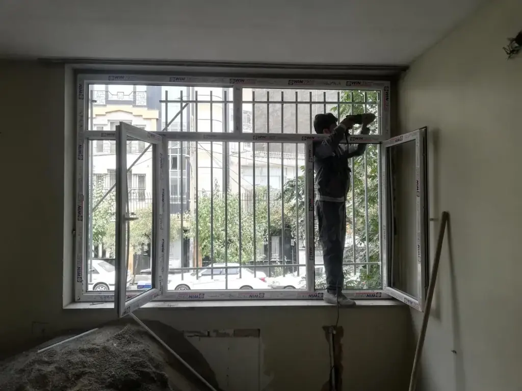 نصاب آریانا در حال تنظیم پنجره UPVC از داخل ساختمان