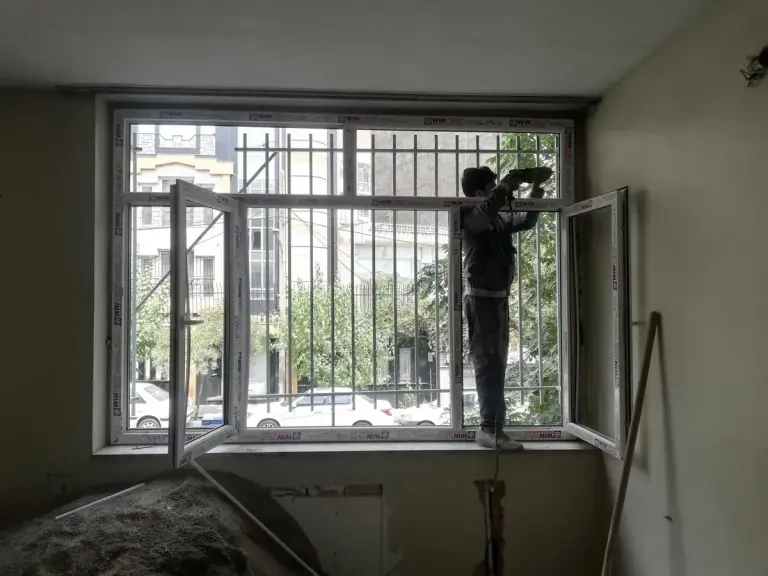 نصاب آریانا در حال تنظیم پنجره UPVC از داخل ساختمان